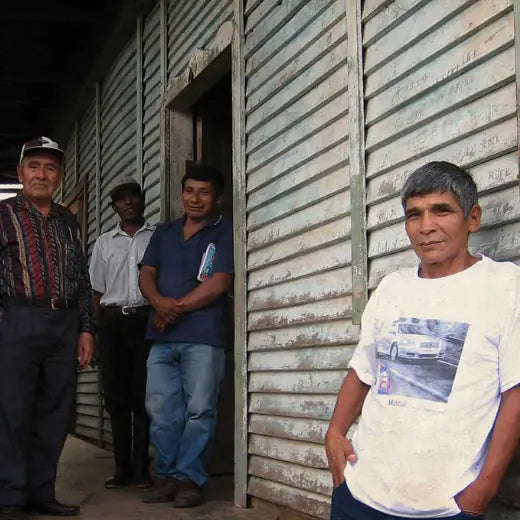 Peruvian coffee farmers, direct trade partners of IncaFé Organic Coffee, standing together outside a rustic wooden building.