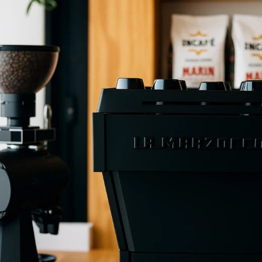 Image of professional coffee set-up, La Marzocco and Mahlkonig grinder with IncaFé Organic Coffee bags in the background