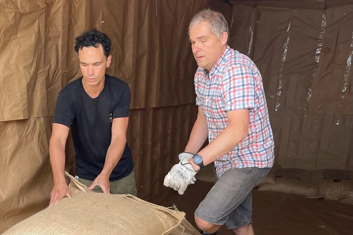 Joop handling organic green coffee sacks at origin